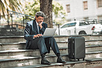 Travel, email and businessman with laptop in the city for communication and booking a flight online. Serious, working and mature corporate manager with a computer and luggage for a ticket on the web