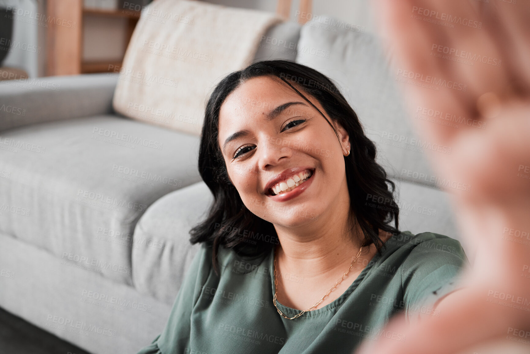 Buy stock photo Selfie, happy and portrait of a woman in her living room relaxing, resting or chilling by the sofa. Happiness, smile and young female person from Mexico taking a picture at her modern home apartment.