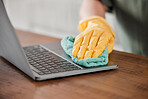 Person, hands and cleaning laptop for disinfection, bacteria or germ removal on wooden table at home. Closeup of housekeeper, cleaner or maid wiping computer in sanitizing, hygiene or clean equipment