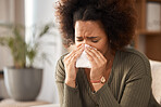 Sick woman, blowing nose and tissue with flu, illness or infection disease in living room at home. Sad, frustrated or ill female person with allergy, sinus or fever sneezing in living room at house