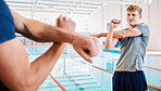 Man, swimmer and stretching with personal trainer for exercise, training or workout by indoor pool. Male person or athlete in body warm up with fitness coach getting ready for swimming competition