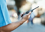 Hand, walkie talkie and a security guard or safety officer outdoor on a city road for communication. Closeup of person with a radio on urban street to report crime for investigation and surveillance