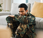 Sad, trauma and male military soldier sitting on the floor in the living room of his house. Depression, ptsd and man army warrior from Mexico thinking about mental health in the lounge at home. 