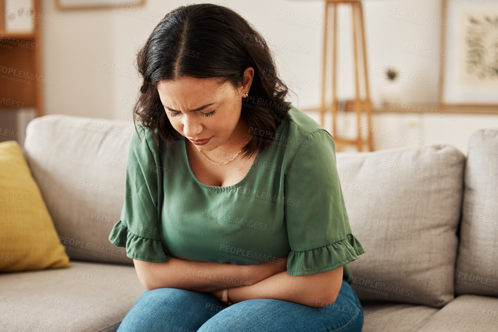 Buy stock photo Stress, stomach pain and woman on a sofa with menstruation, gas or constipation, pms or nausea at home. Gut health, anxiety and lady with tummy ache in living room from ibs, bloated or endometriosis