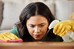 Face, spray bottle and a woman cleaning a wooden surface in her home for hygiene or disinfection. Gloves, product or bacteria and a cleaner with focus using detergent to spring clean in an apartment