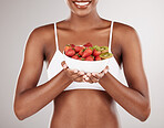 Woman, hands and diet with bowl of fruit for natural nutrition against a white studio background. Closeup of female person holding organic strawberry, kiwi or salad to lose weight or healthy wellness