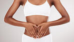 Heart shape, hands and stomach of a woman for health and wellness on a white studio background. Fitness, gut and diet of aesthetic female model for weight loss, balance or digestion and motivation