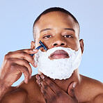 Shaving beard, cream and portrait of a black man on a blue background for grooming and beauty. Serious, spa and face of an African person with a razor for hair removal and cleaning on the face