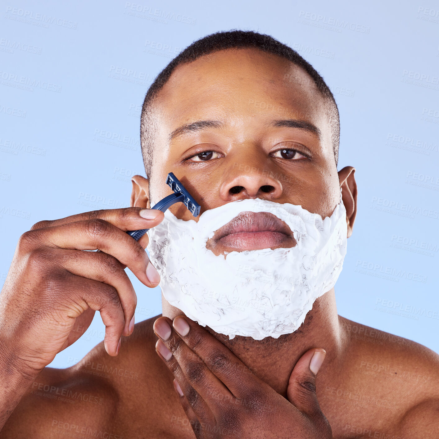 Buy stock photo Shaving beard, cream and portrait of a black man on a blue background for grooming and beauty. Serious, spa and face of an African person with a razor for hair removal and cleaning on the face