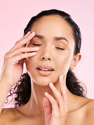 Buy stock photo Skin, beauty and hands on face of a woman in studio for cosmetics, dermatology and glow. Headshot, moisturizer and touch for natural skincare of a young female aesthetic model on a pink background