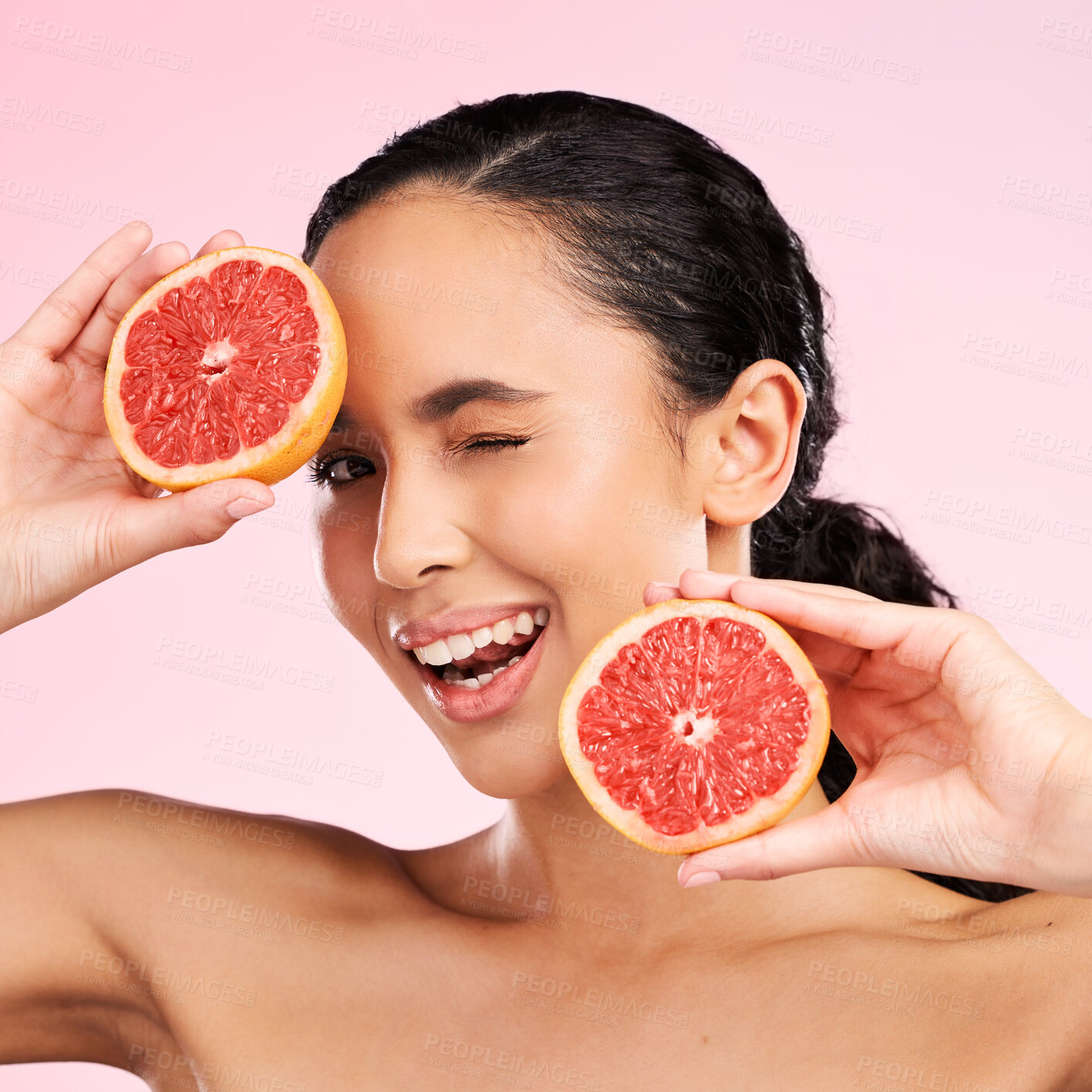 Buy stock photo Face, beauty and woman wink with grapefruit in studio isolated on a pink background. Portrait, natural cosmetic and model with fruit, food or nutrition for skincare, healthy vegan diet or vitamin c