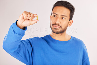 Buy stock photo Healthcare, showing and a man with a pill on a studio background for a virus, covid or supplement. Sick, medical and an Asian person with a tablet, medication or vitamin c medicine for wellness