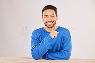 Buy stock photo Smile, table and portrait of a man happy to relax on a desk feeling confident isolated in a studio white background. Resting, calm and young male person looking handsome, friendly and with style