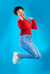 Excited, jump and woman portrait with winner, deal and smile in a studio. Wow, energy and up in the air with female person and blue background with celebration for sale announcement and big news