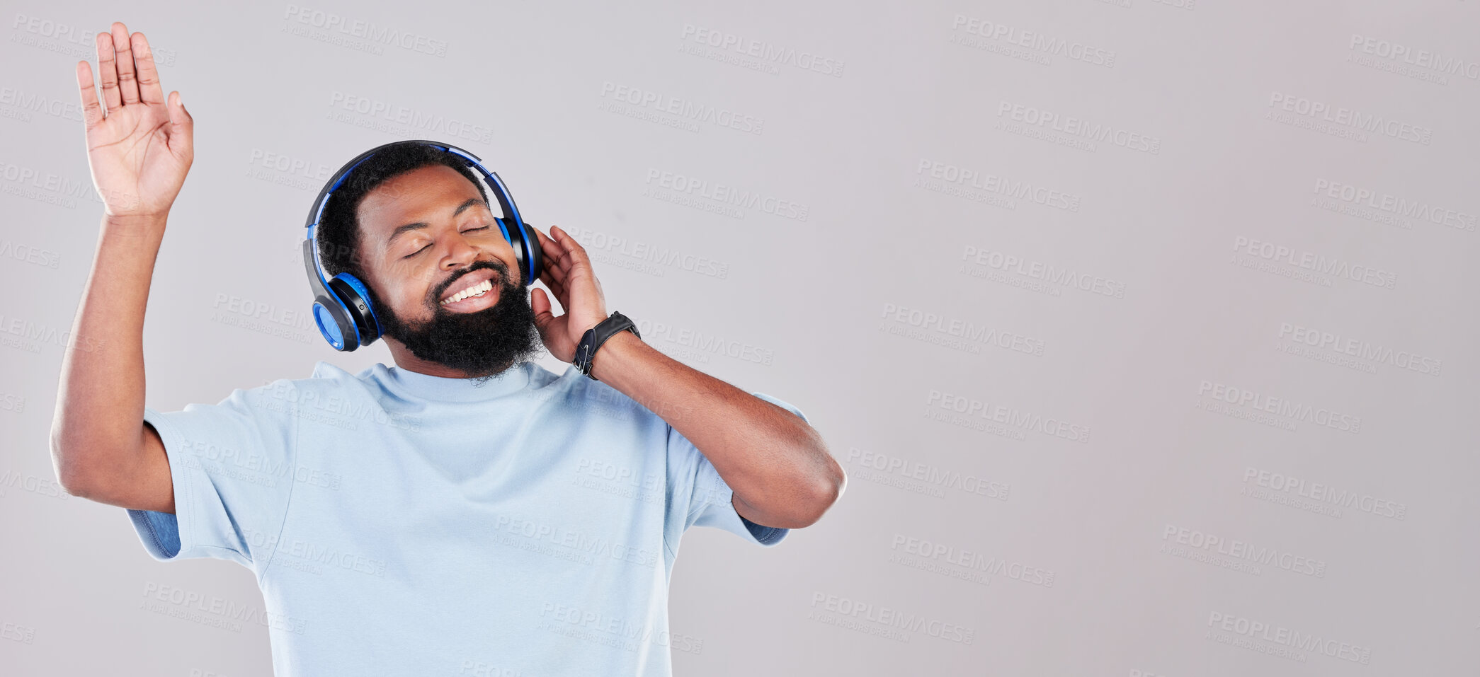 Buy stock photo Headphones, happy and young man in a studio listening to music, playlist or album while dancing. Happiness, smile and African male model streaming song or radio by gray background with mock up space.