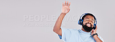 Buy stock photo Headphones, mockup and young man in a studio listening to music, playlist or album while dancing. Happy, smile and African male model streaming a song or radio by a gray background with mock up space