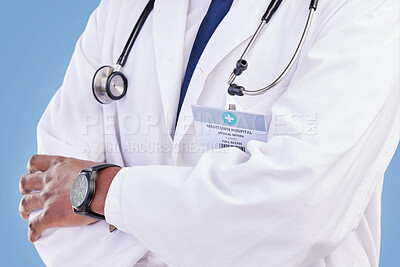 Buy stock photo Doctor, stethoscope and arms crossed in studio with a medical expert or healthcare worker on blue background. Surgeon, hands and confidence in medicine or pharmaceutical research in hospital