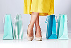 Shoes, shopping bag and a woman in studio for fashion sale, promotion or retail discount, Legs of a female model or customer on a white background for advertising commerce offer, paper bags or gift 