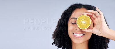 Buy stock photo Skincare, wellness and woman with lemon eye or fruit for nutrition in grey studio background or banner. Dermatology, hand and smile with girl or vitamin c for natural facial or diet in mockup space.