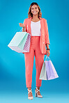 Portrait, fashion and shopping bags with a woman customer in studio on a blue background for consumerism. Smile, retail and sale with a happy young female shopper buying luxury goods on promotion