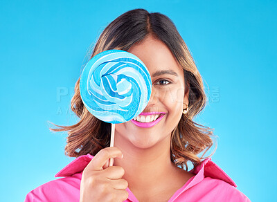 Buy stock photo Portrait, lollipop or happy woman on a blue background in studio with positive, sugar or cheerful smile. Colorful sweets, hungry or face of Indian girl eating a giant snack, treats or candy with joy