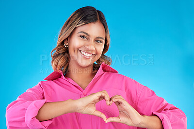 Buy stock photo Woman, heart shape and smile portrait in studio for love, fashion or happiness. Happy person show sign with hands, icon or emoji for support, kindness and motivation for charity on a blue background