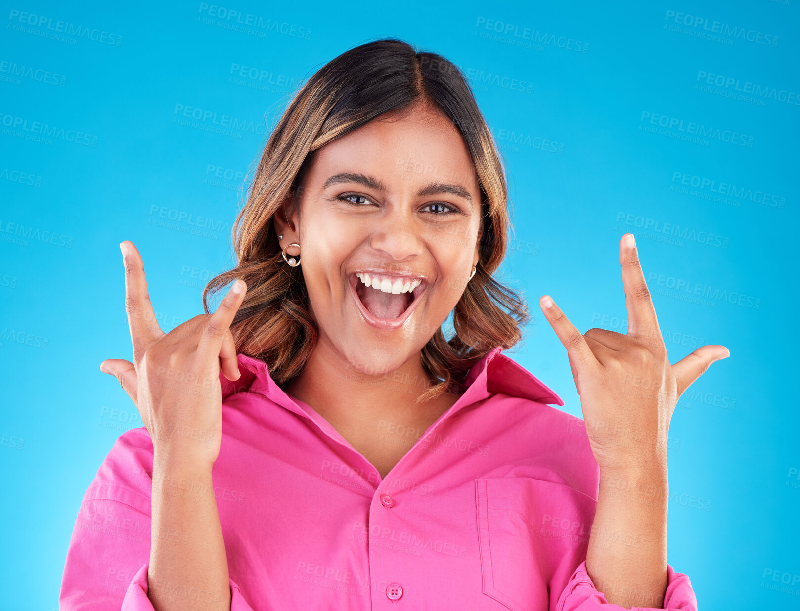 Buy stock photo Happy, portrait and woman with rocker hands in studio for freedom, fun and positive attitude on blue background. smile, face and female with rockstar emoji, sign or punk gesture, good mood or vibes