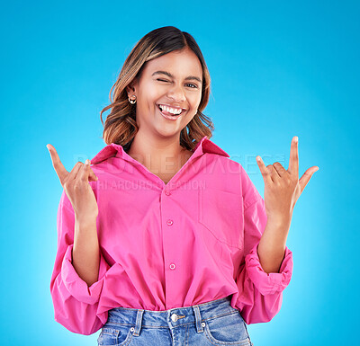 Buy stock photo Wink, portrait and woman with rocker hands in studio for freedom, happy and positive attitude on blue background. Smile, face and female with rockstar emoji, sign or punk gesture, good mood or vibes
