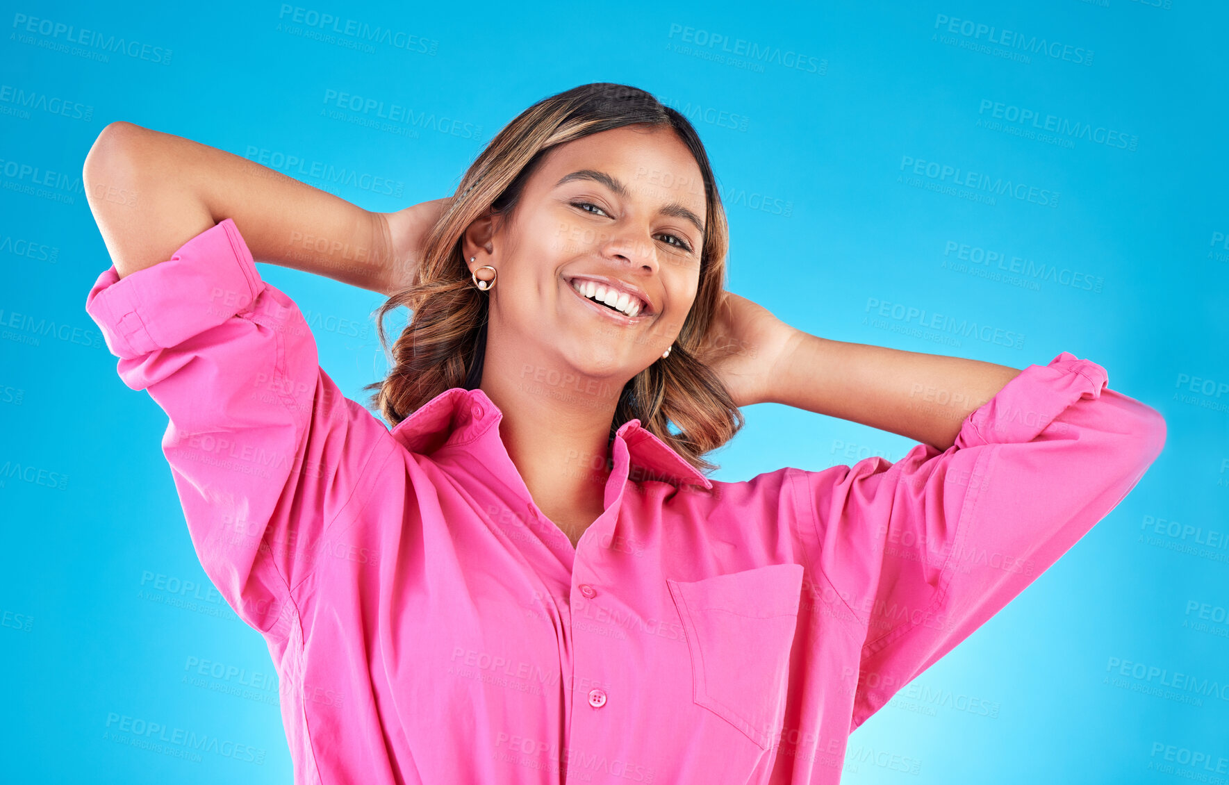 Buy stock photo Woman, happy portrait and fashion in studio with beauty, cosmetics and natural makeup. Young Indian female model person with hands behind head on blue background with casual style clothes to relax