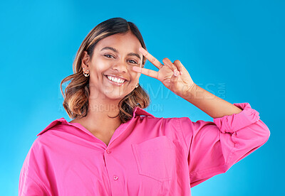 Buy stock photo Smile, happy and peace sign with portrait of woman in studio for support, gen z and emoji. Motivation, kindness and winner with face of person on blue background for v icon, positive and symbol
