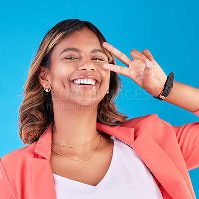 Buy stock photo Peace sign, happy and portrait of a woman on a blue background for fashion, comedy and young. Smile, face and an Indian girl or model with a hand gesture for crazy isolated on a studio backdrop