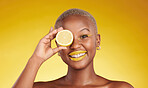 Happy black woman, portrait and lemon for vitamin C or natural beauty against a yellow studio background. African female person smile with organic citrus fruit for diet or detox with facial makeup