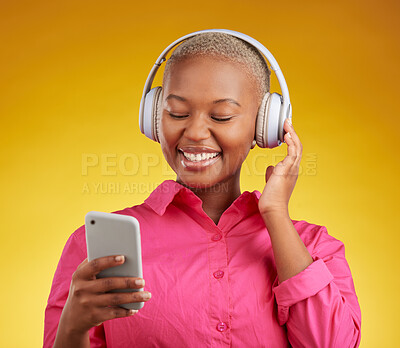 Buy stock photo Happy, phone and black woman with music headphones in studio for streaming, track or selection on yellow background. Radio, podcast and African lady online with smartphone for audio subscription app
