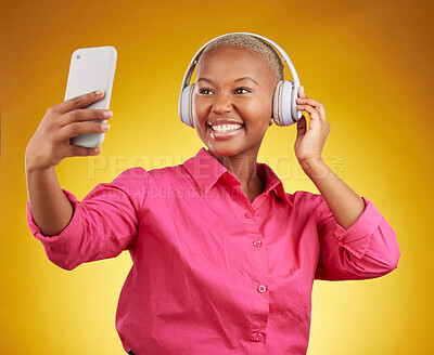 Buy stock photo Smile, selfie and black woman with headphones for music, radio and podcast in studio isolated on a yellow background. Profile picture, photographer and African person or influencer on social media