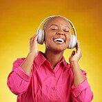 Music headphones, happy and black woman singing in studio isolated on a yellow background. African person, smile and listening to radio, jazz and streaming audio, podcast and hearing sound of hip hop