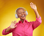 Happy, music headphones and black woman dance in studio isolated on a yellow background. African person, smile and listen to radio, singing and streaming audio, podcast or hearing sound with energy