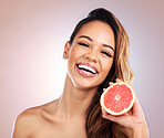 Happy woman, portrait and grapefruit for vitamin C in skincare against a studio background. Face of female person or model smile with organic fruit for natural nutrition, diet or healthy wellness 