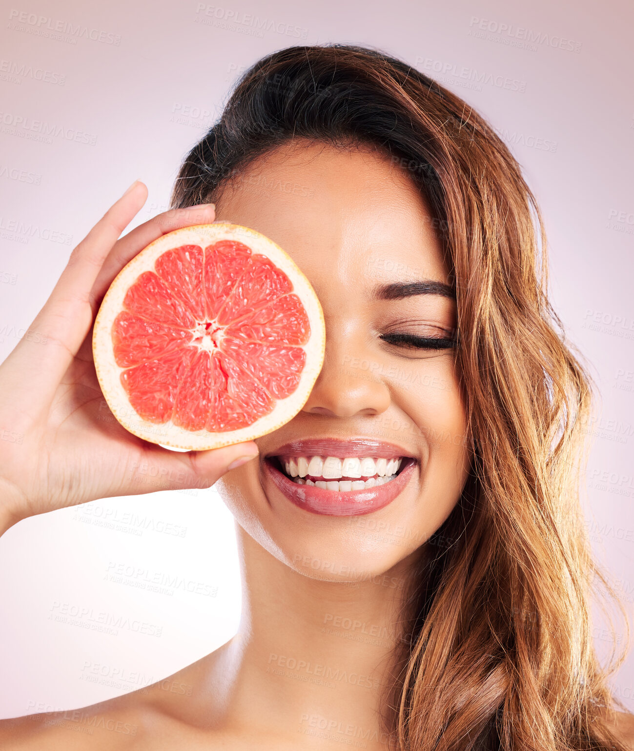 Buy stock photo Citrus, grapefruit and face of woman with healthy, natural or organic beauty isolated in a brown studio background. Excited, eyes and young female person with vitamin c for skincare or detox