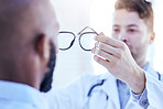 Hands, man and optometrist with glasses for eye support and lens check at a doctor consultation. Medical, wellness and back of patient with vision and eyewear care with professional holding frame