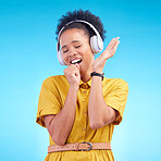 Happy woman, headphones and singing while listening to music for karaoke against a blue studio background. Female person enjoying audio sound track or song with headset for entertainment on mockup