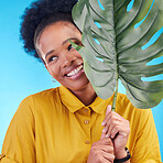 Fashion, happy and black woman with plant on blue background for cosmetics, makeup and beauty. Nature, studio and female person with monstera leaf for organic, natural and detox products for wellness