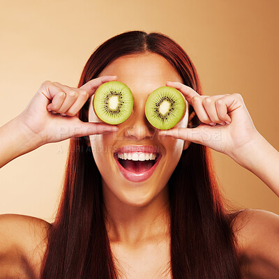 Buy stock photo Beauty, kiwi and a woman with skin care in studio for natural dermatology, cosmetics or glow. Facial, fruit and healthy diet for vitamin c and nutrition of excited model person on a brown background 