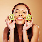 Kiwi, beauty and face a woman with skin care in studio for natural dermatology, cosmetics or glow. Facial, fruit and healthy diet for vitamin c and nutrition of model person on a brown background 