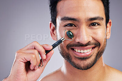 Buy stock photo Happy man, portrait or face massage with roller or product for healthy skincare on studio background. Cheek, crystal stone treatment or male model with facial dermatology cosmetic for beauty glow