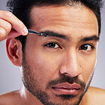 Eyebrow, tweezer and portrait of a man in studio for beauty, hygiene or grooming. Hair removal, epilation and face of serious asian person for skincare, self care or cosmetic tools on grey background