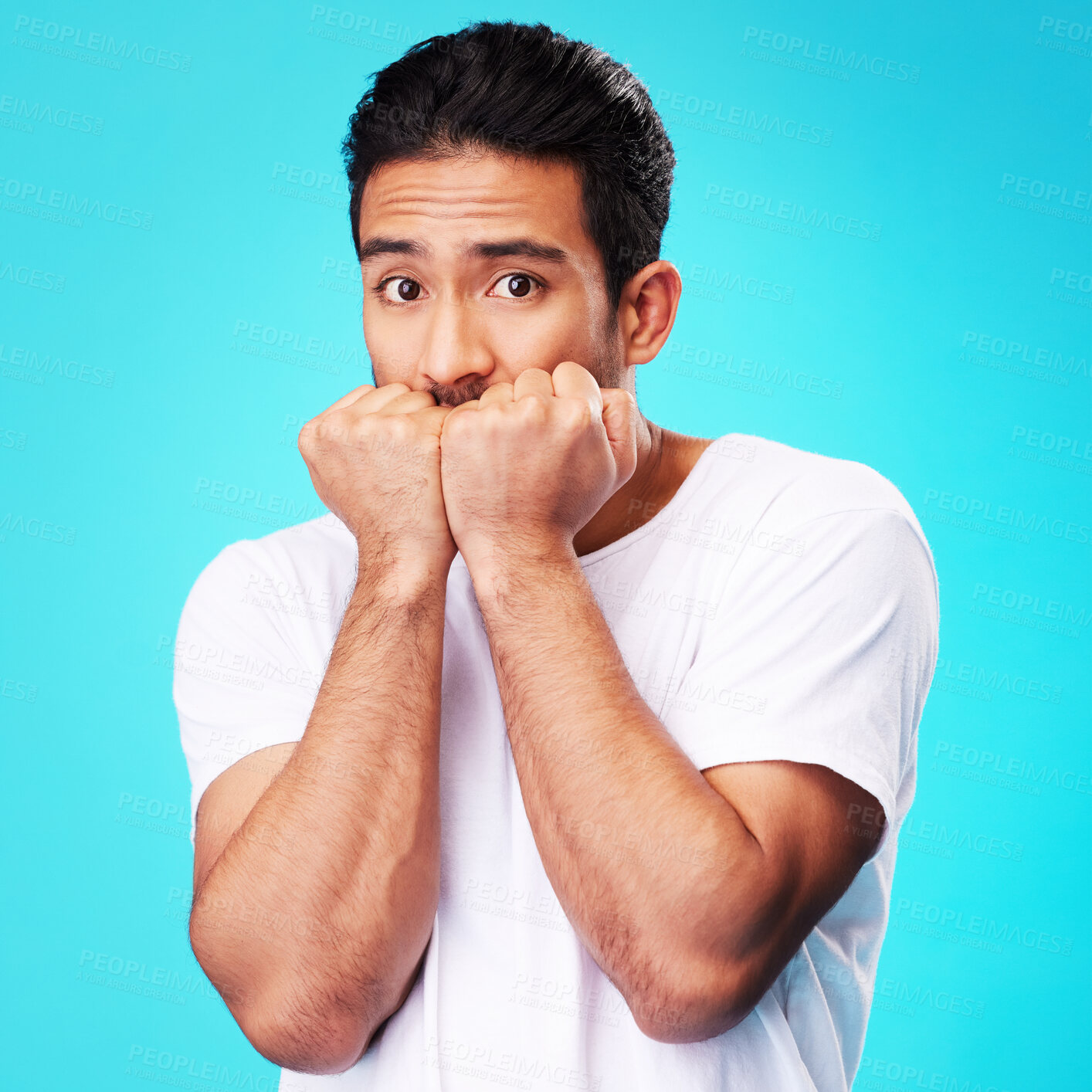 Buy stock photo Fear, scared and portrait of man nervous, anxiety or anxious due to crisis or stress isolated in a studio blue background. Worry, suspense and young male person hands in face for mistake reaction