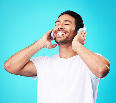 Buy stock photo Music, headphones and happy man listening in studio isolated on a blue background. Radio, smile and person with audio, sound or hearing podcast, jazz or media for hip hop with eyes closed for freedom