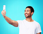 Asian man, selfie and smile in studio for social media post, web chat and excited by blue background. Young guy, student or influencer with memory, profile picture and photography for update on blog