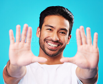Buy stock photo Portrait, hands and man frame face in studio to review profile picture on blue background. Happy young asian model planning perspective of photography, selfie and creative inspiration for border sign