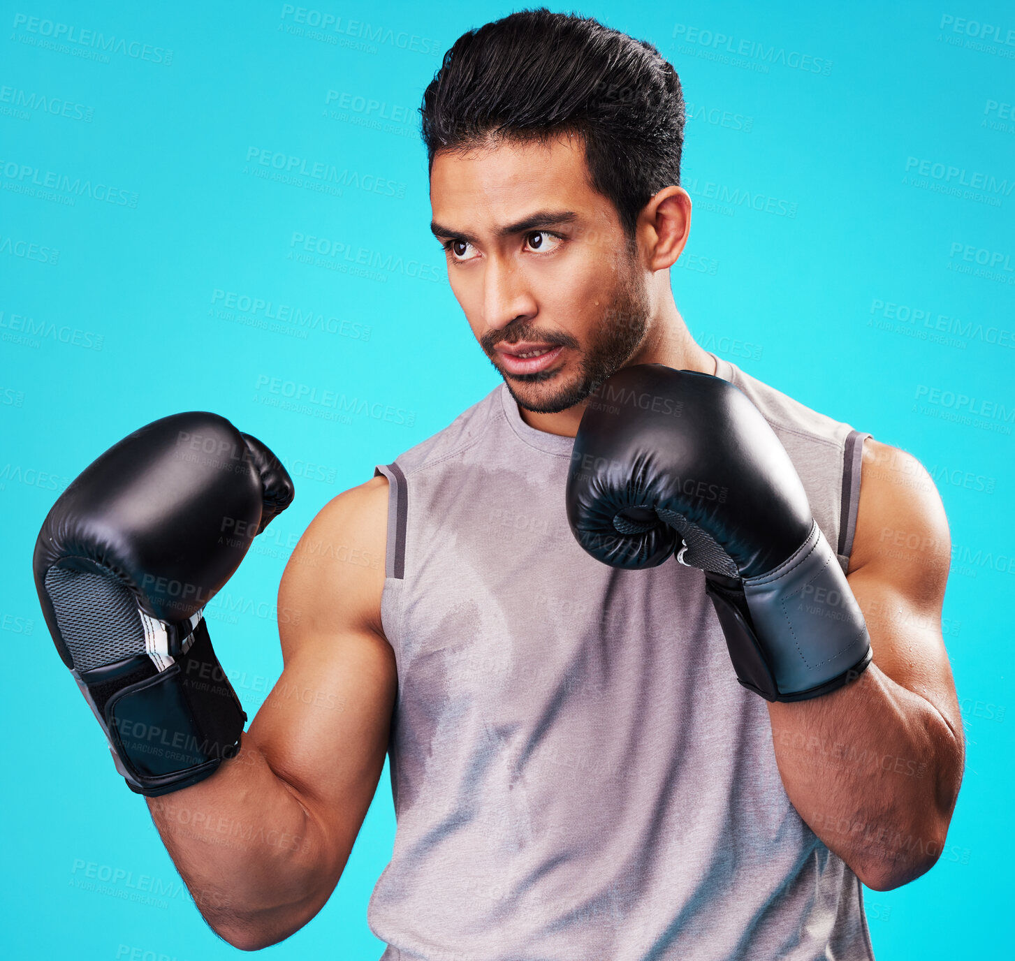 Buy stock photo Boxing, man and fighter training, sports and energy against a blue studio background. Asian person, boxer or serious athlete with power, strong and challenge with workout gloves, fight or competition